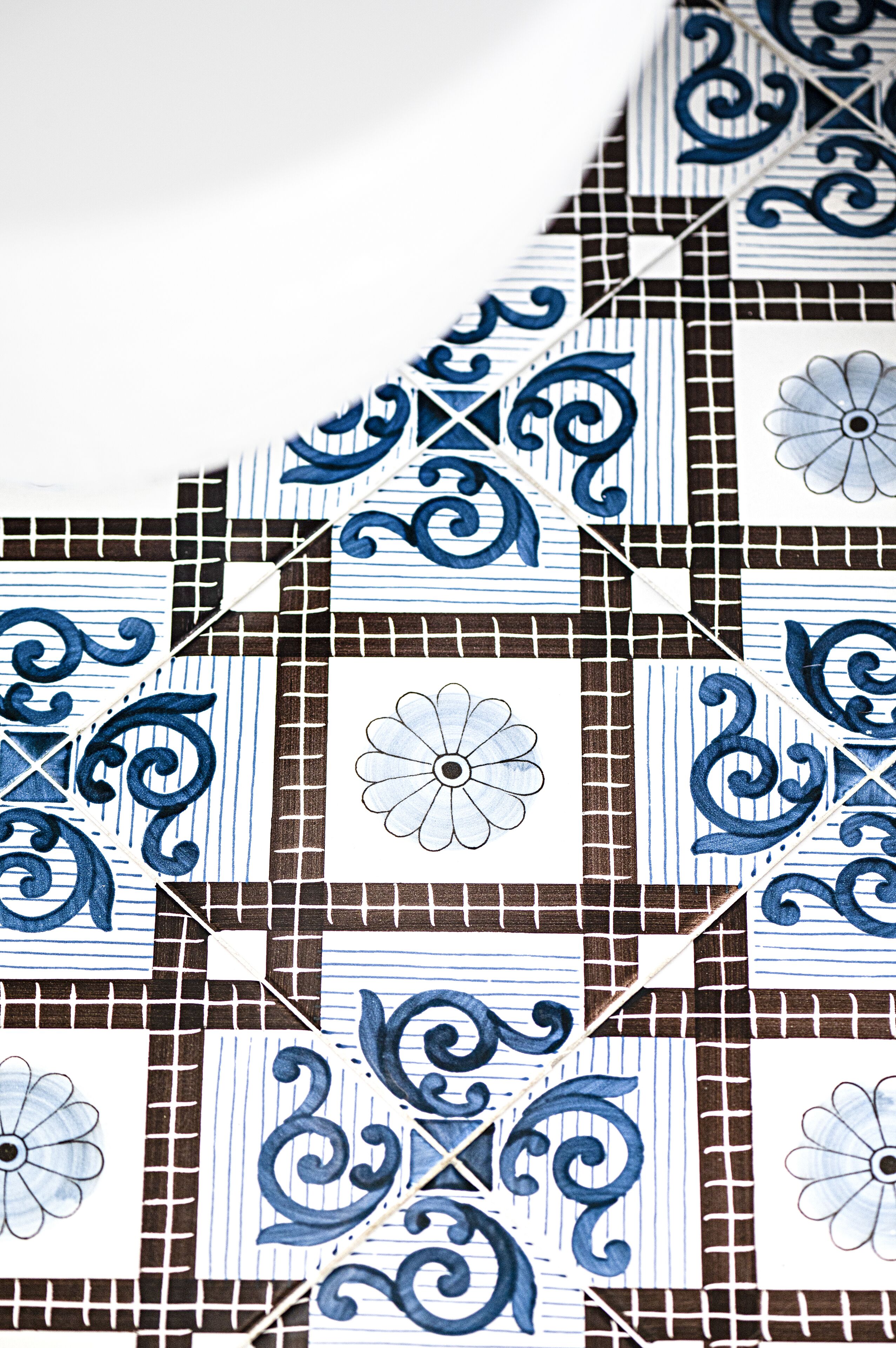 Ein Detailaufnahme einer gefliesten Oberfläche mit blau-weißen Mustern, darunter floralen Elementen und geometrischen Formen.
