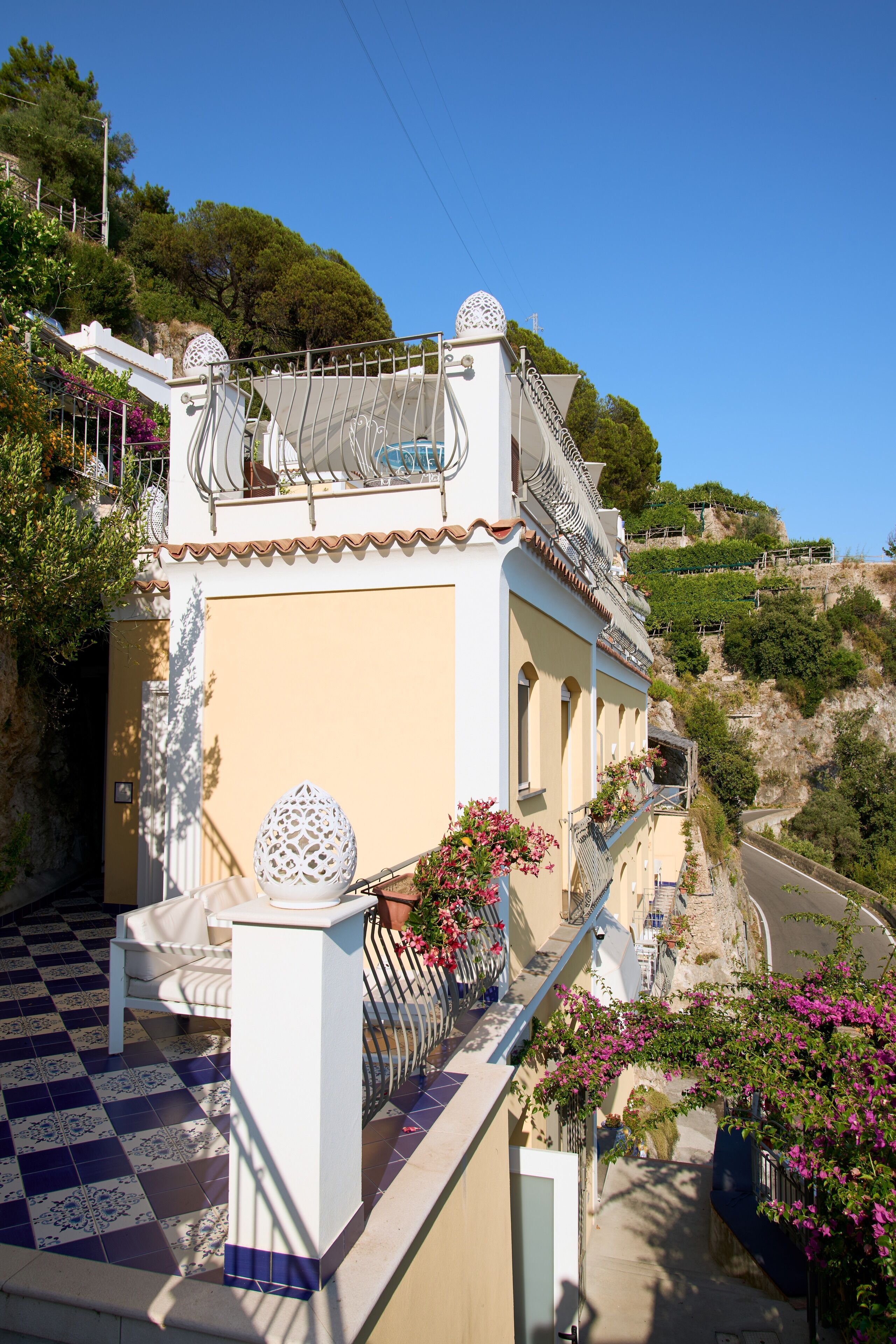 Um edifício com chão quadriculado, varanda com guarda-corpo e um objeto branco decorativo na fachada.