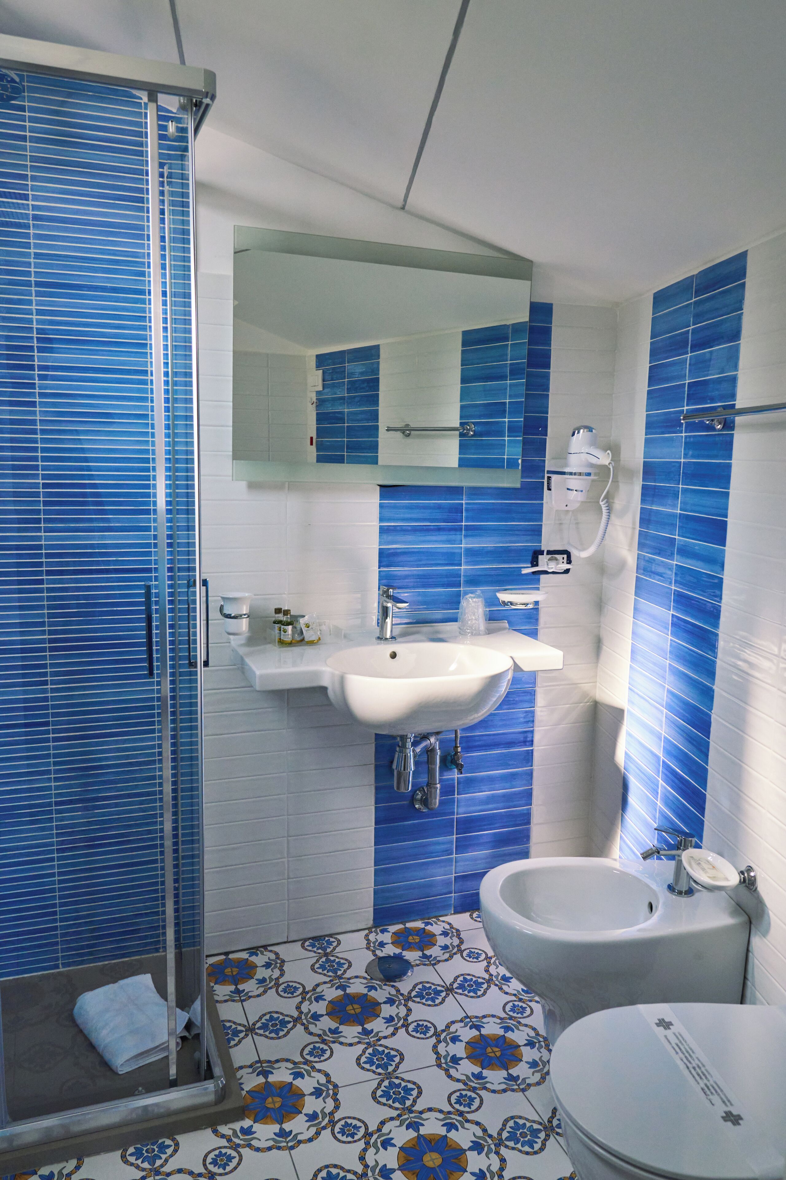 Un baño con ducha, lavabo, inodoro y espejo.