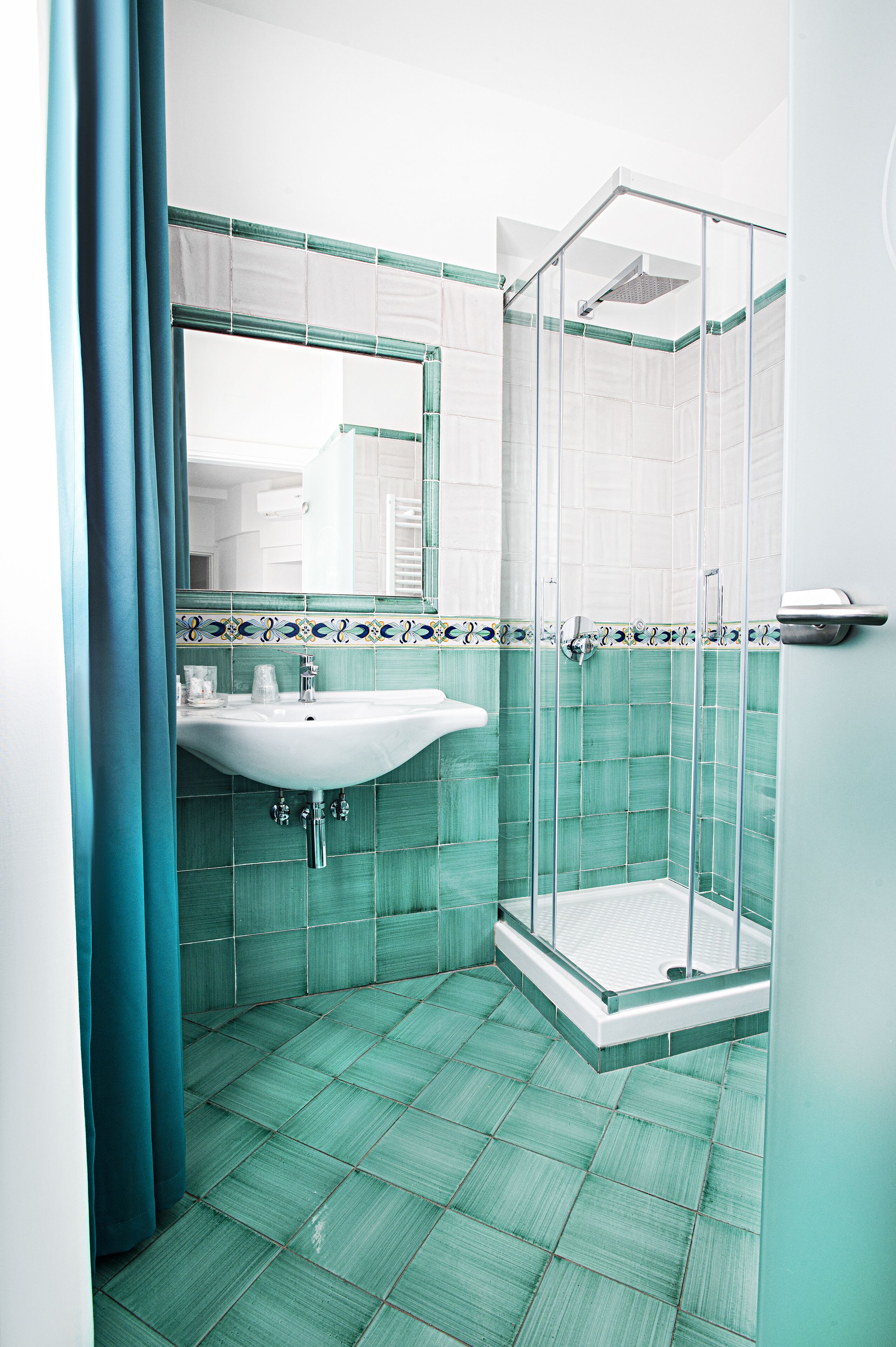 A bathroom with a sink, shower, and tiled floor.