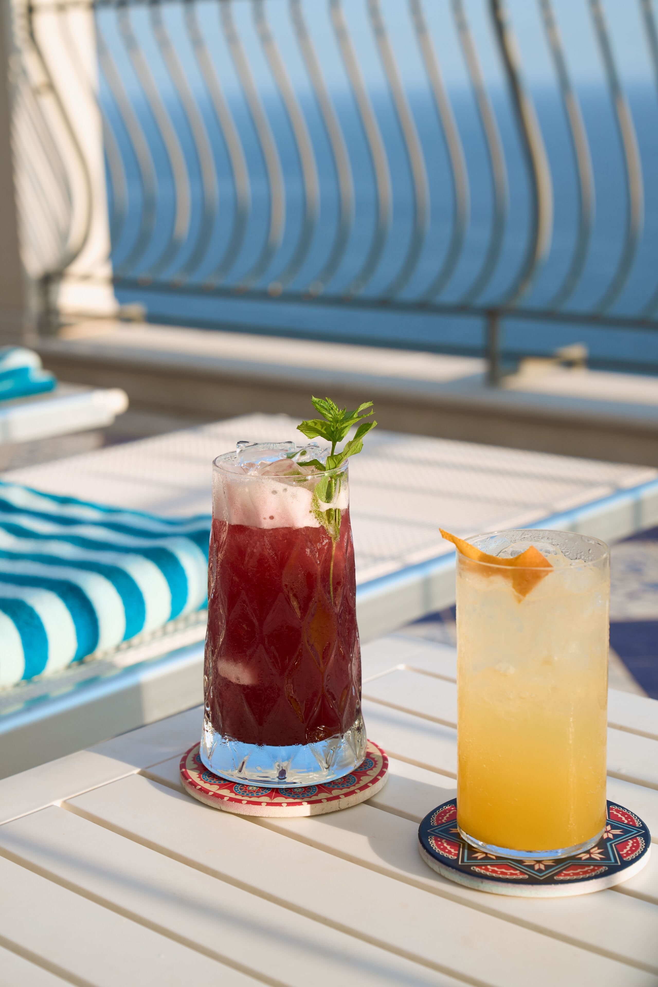 Dos bebidas sobre una mesa con un cojín a rayas al fondo.