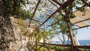 A stone pathway leading to a wooden pergola with a view of the sea. - Hotel Villa Pandora (Maiori)
