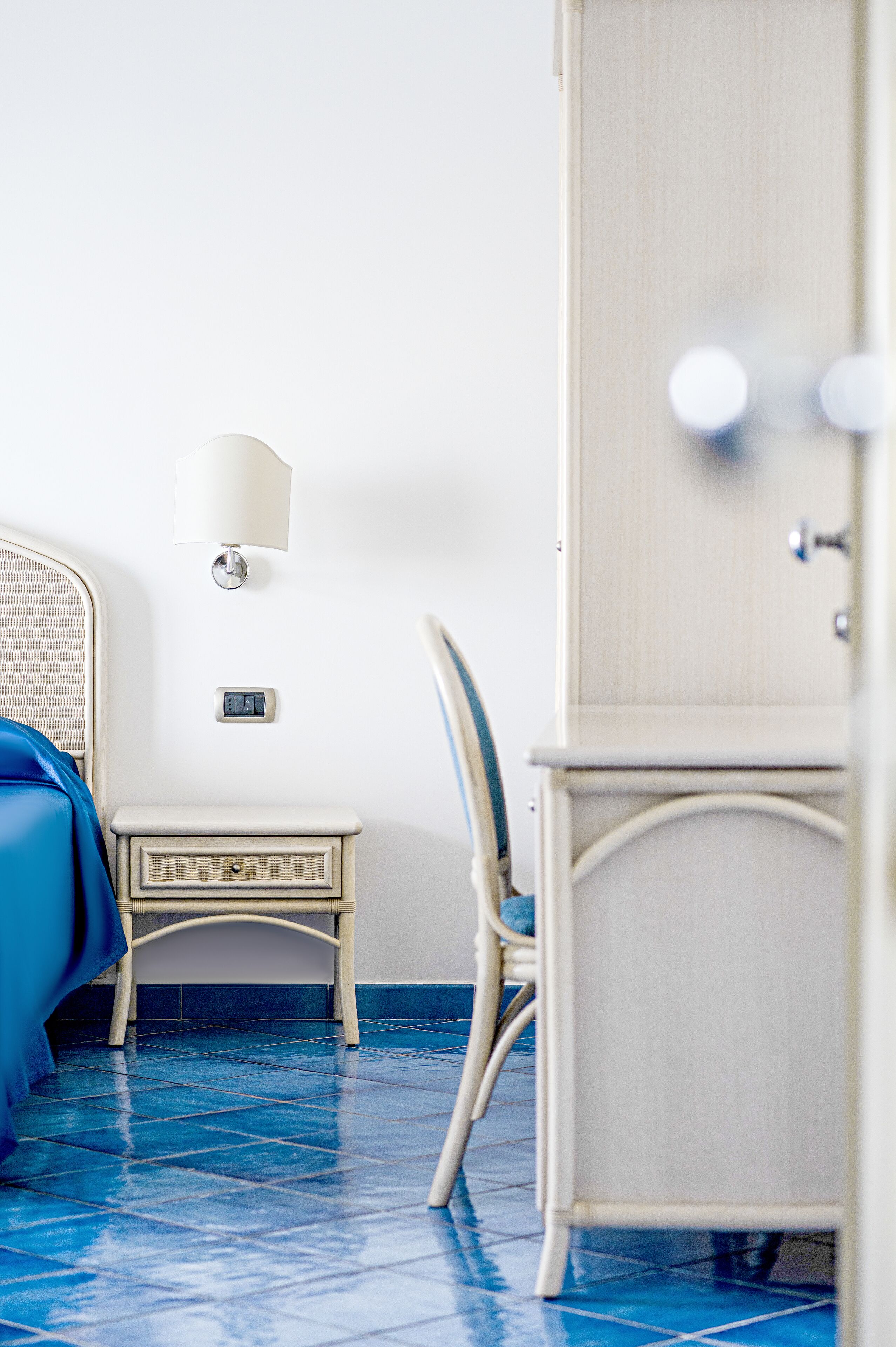 A room with a bed, a bedside table, a lamp, and a wardrobe.