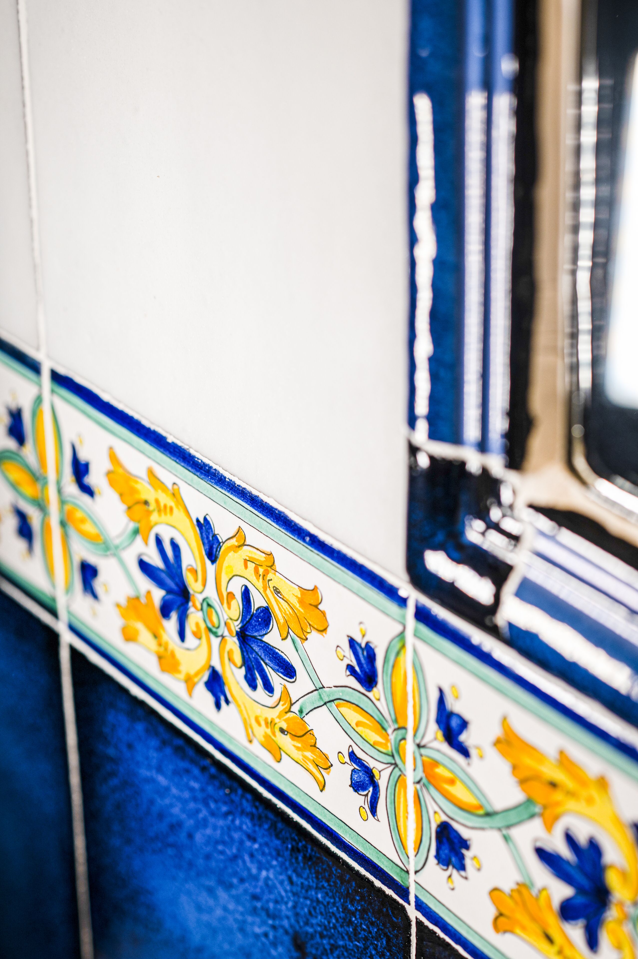 A close-up of a tiled wall with a floral pattern.