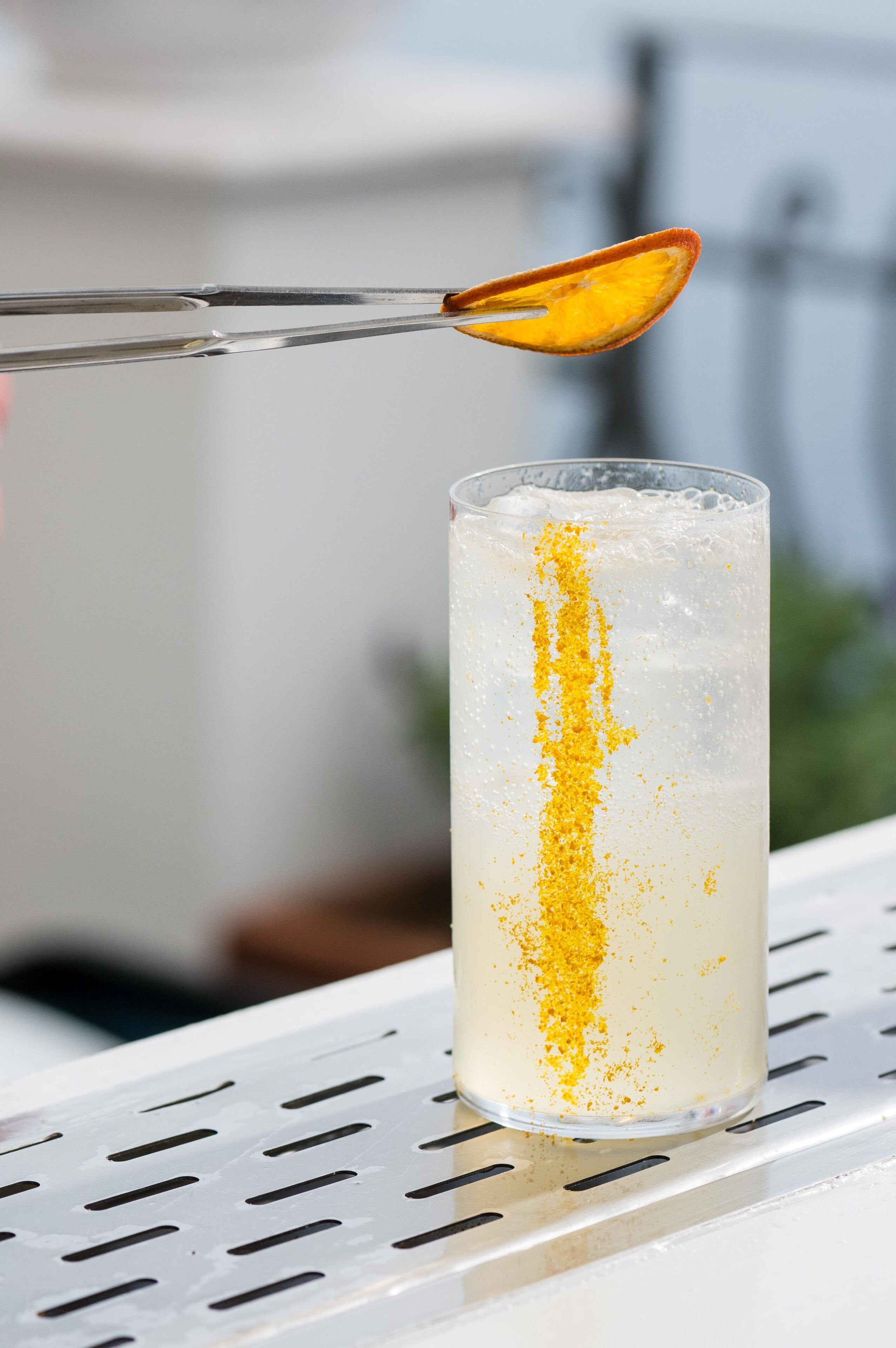 Un vaso alto con un adorno amarillo sobre una superficie metálica.
