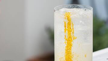 Un vaso alto con un adorno amarillo sobre una superficie metálica.