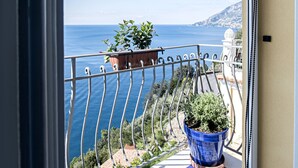 A balcony with a potted plant, a tiled floor, and a view of the sea. - Hotel Villa Pandora (Maiori)