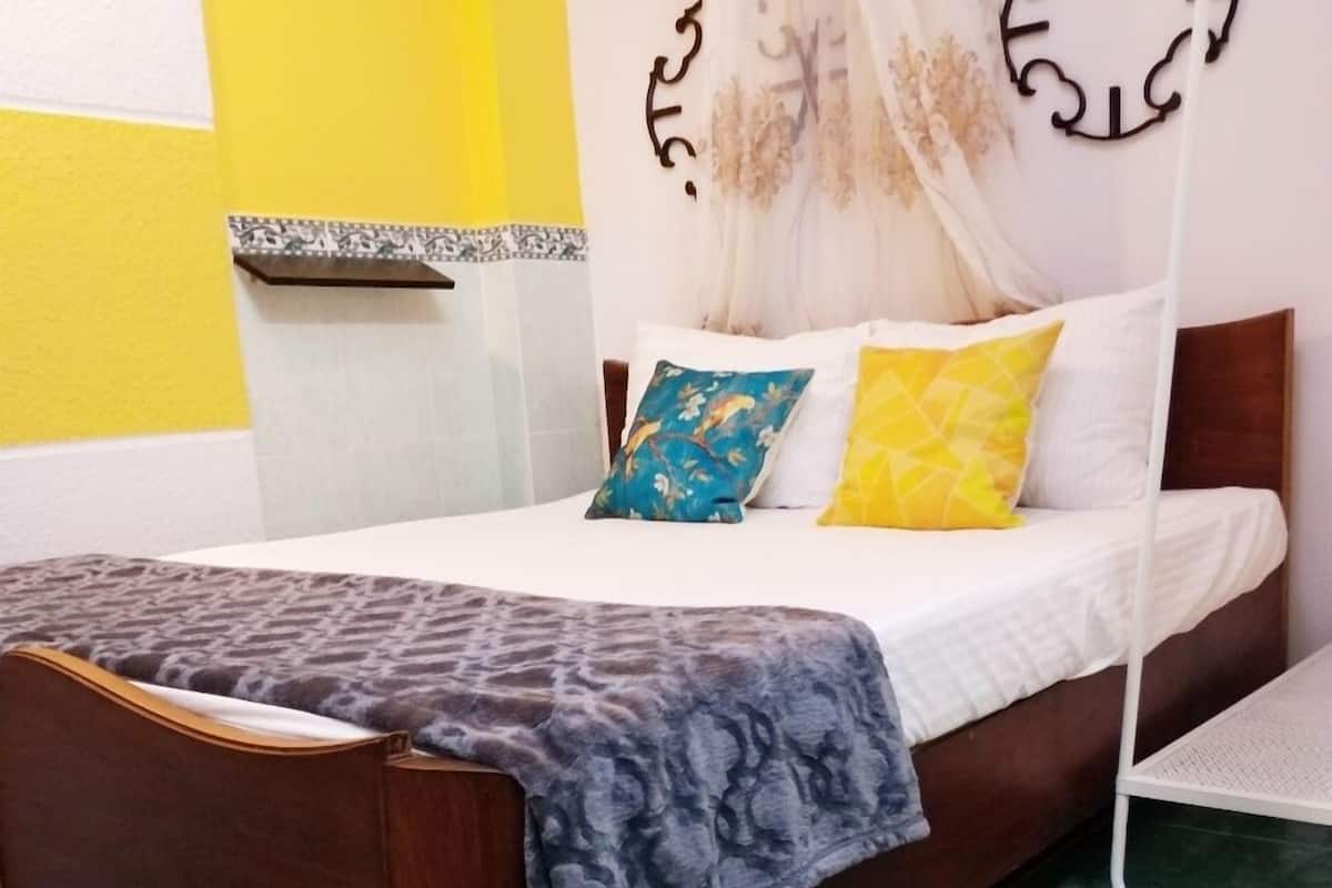 Uma cama com cabeceira de madeira, dossel e duas almofadas.