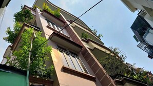 Een meerlaags gebouw met balkons, een groene deur en wat beplanting.