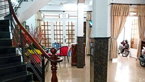 Een hotellobby met een trap, een receptiebalie en een motorfiets vlakbij de ingang.