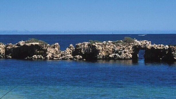 A coastal scene with a rocky breakwater extending into the sea, clear blue water, and a sandy beach. - Sharpie’s Family Shack 🏝 Greenhead.   ☀️ Free Wi-Fi (Green Head)