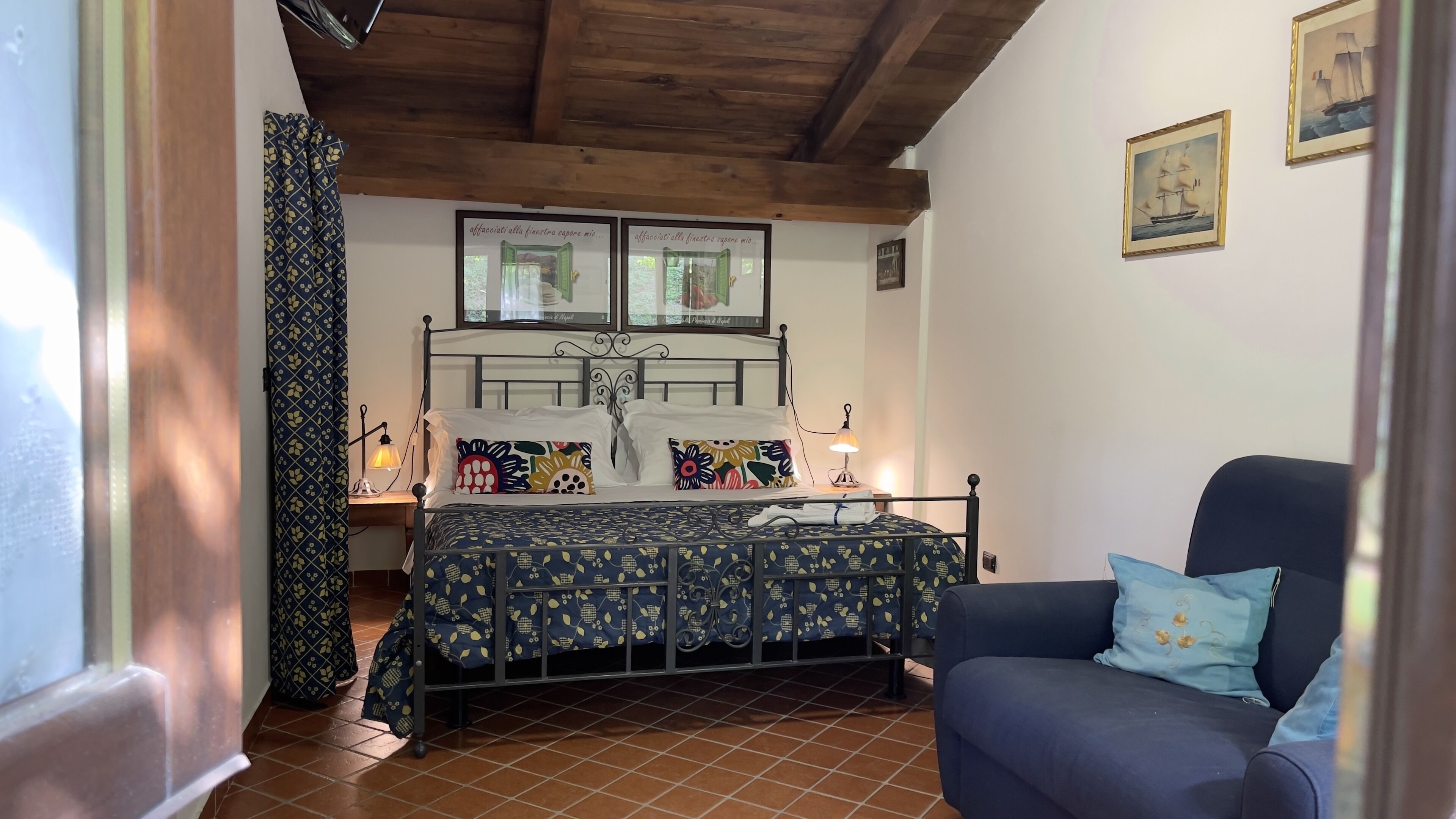 A bedroom with a bed, a chair, a nightstand, and a window with curtains.