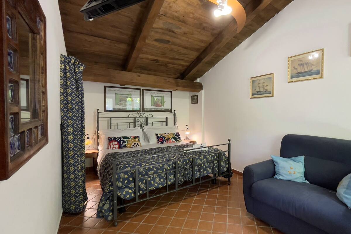 A bedroom with a bed, a sofa, and a wooden ceiling.