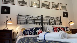 Habitació d'hotel amb dos llits, cadascun amb coixí de disseny únic, una làmpada de nit i una fotografia emmarcada a la paret.