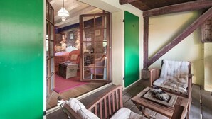 Une pièce chaleureuse avec un plafond en bois, une porte verte, un fauteuil en osier et une table sur laquelle se trouve un bol.