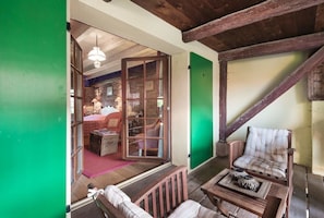 Cozy room with exposed beams, comfortable seating area, and a green door leading to another space.