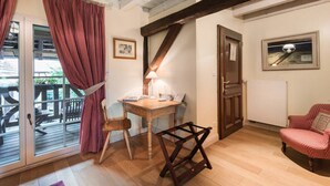 Une pièce chaleureuse avec un bureau en bois, une chaise, une lampe et une vue sur une terrasse extérieure, accessible par une porte vitrée.