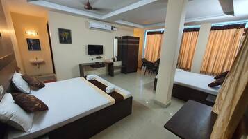A hotel room with two beds, a desk, a TV, and a wardrobe.