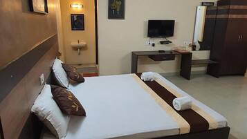 Una habitación de hotel con una cama grande, mesitas de noche, televisión, aire acondicionado y un armario.