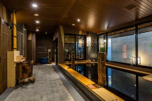 A modern interior with a wooden ceiling, a long bench, and a view through large windows. - Onyado Nono Asakusa Natural Hot Springs (Tokyo)