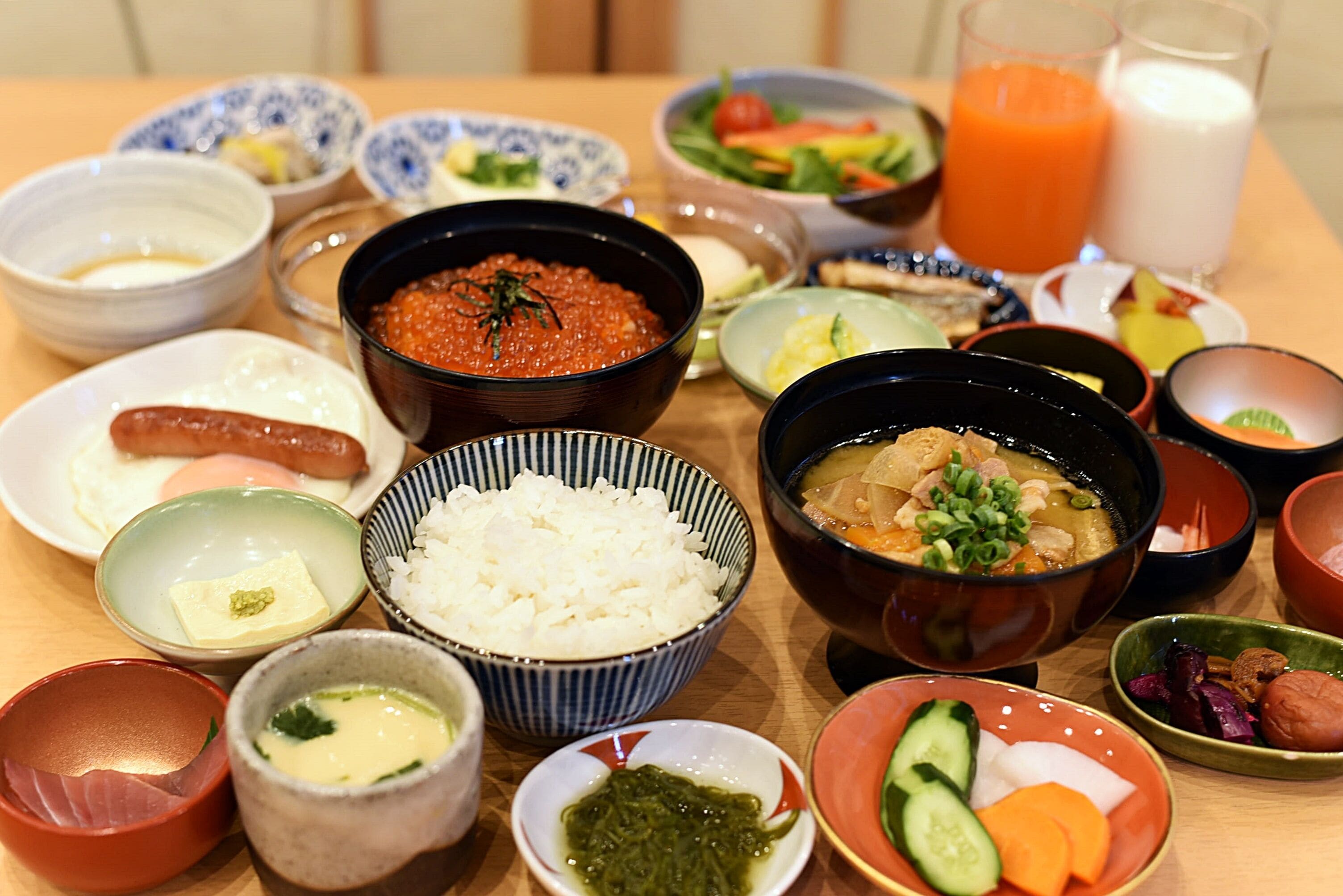 A variety of dishes including rice, soup, and vegetables, served on a wooden table.