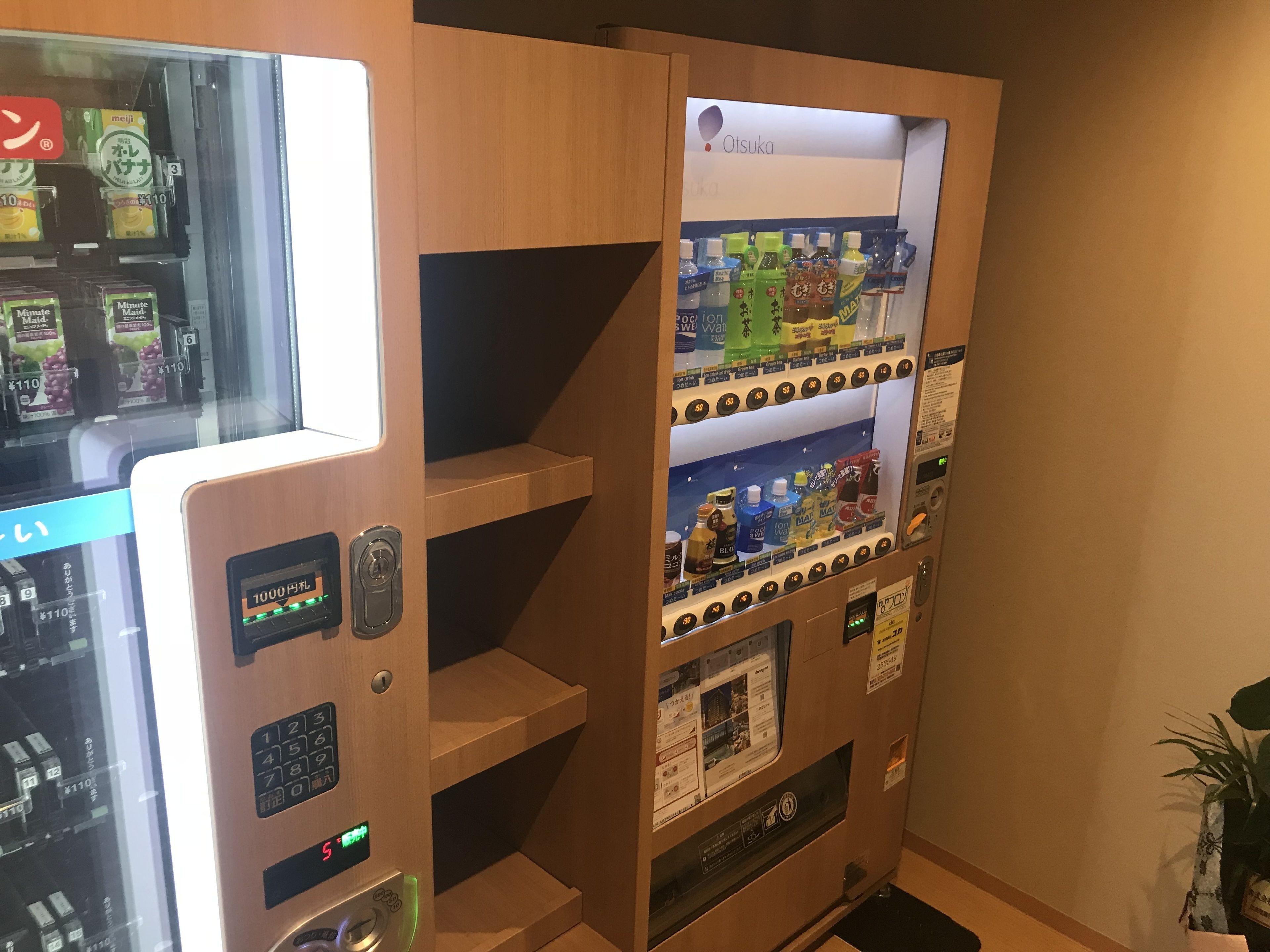 Een automaat met diverse dranken en snacks, een digitaal scherm en een muntinworp.