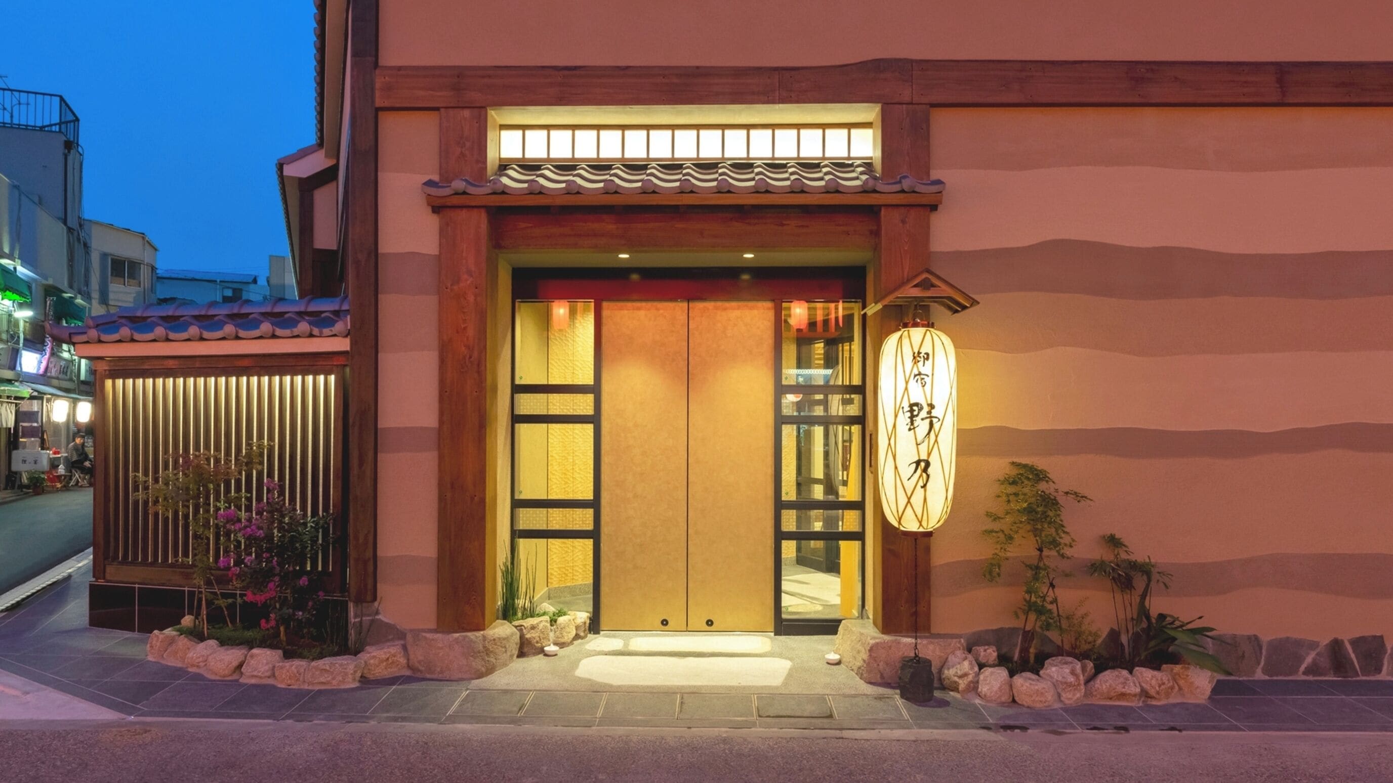 Un bâtiment traditionnel japonais, avec une entrée en bois, un toit recouvert de tuiles et une enseigne ornée de caractères japonais.