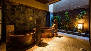 A spa area with stone walls, wooden beams, and large copper tubs. - Onyado Nono Asakusa Natural Hot Springs (Tokyo)
