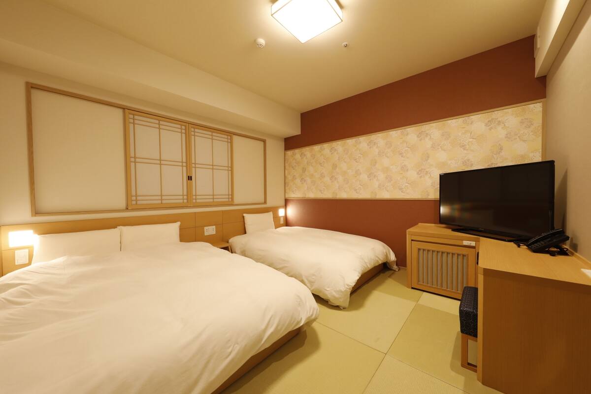 A hotel room with two beds, a television, a desk, and a cabinet.