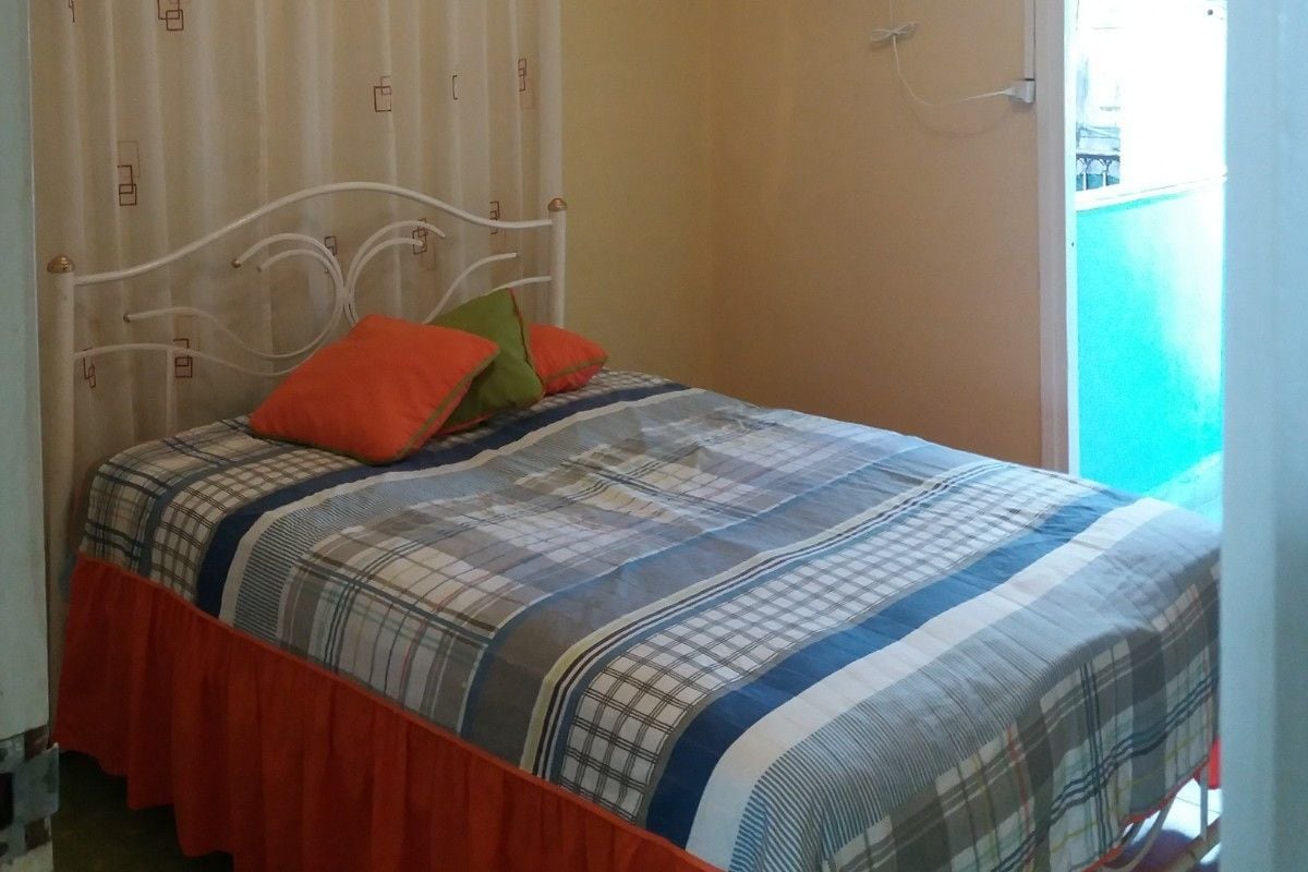 Ein Schlafzimmer mit einem Bett, einem Deckenventilator und einem Fenster.