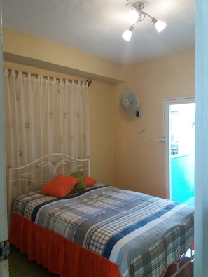 Ein Schlafzimmer mit einem Bett, einem Deckenventilator und einem Fenster.