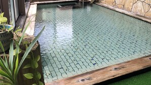 Una piscina con cubierta de madera y vistas a una valla y árboles.