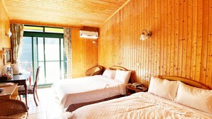 Une cabane en bois avec deux lits, un coin repas et une grande fenêtre.