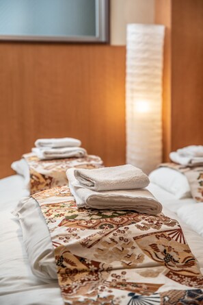 Una cama bien hecha con un edredón estampado y toallas dobladas.