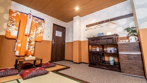 A traditional Japanese room with tatami flooring, a shoji screen, a wooden cabinet with tea set, and a refrigerator. - Kujira Vip (Osaka)