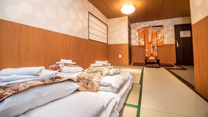 A traditional Japanese room with tatami mats, a shoji screen, and a futon bed. - Kujira Vip (Osaka)