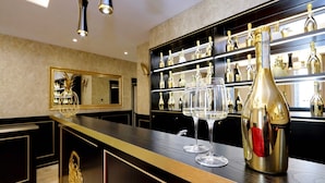 A bar area with a long counter, a mirror, and shelves with bottles and glasses. - Spanish Diamond Luxury Suites & Jacuzzi (Rome)