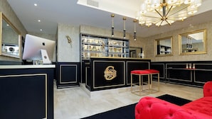 A modern bar area with a black and gold color scheme, a red cushioned seating area, and a chandelier. - Spanish Diamond Luxury Suites & Jacuzzi (Rome)