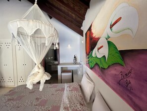 Un dormitorio con cama con dosel, escritorio y un mural en la pared.