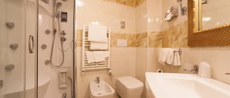 A bathroom with a glass-enclosed shower, a bidet, a toilet, and a bathtub.