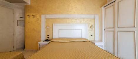 A bedroom with a large bed, a nightstand, a dresser, and a wardrobe.