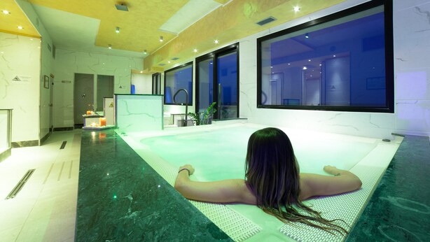 A person relaxing in a large indoor swimming pool with a view of the night sky through large windows. - Hotel Diplomat Palace (Rimini)