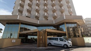 A modern building with a prominent entrance, large windows, and a white van parked in front. - Hotel Diplomat Palace (Rimini)