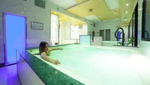 A spa area with a large hot tub, a reception desk, and a reception area with a counter and seating. - Hotel Diplomat Palace (Rimini)