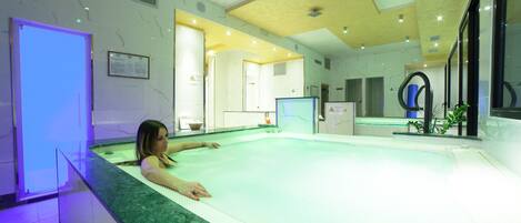 A spa area with a large hot tub, a reception desk, and a reception area with a counter and seating.