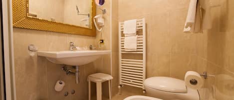 Baño con lavamanos, inodoro y perchero para toallas.