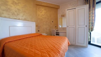 A bedroom with a large bed, a desk, and a wardrobe.