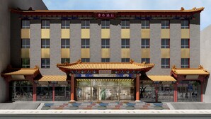 Un hotel con elementos arquitectónicos tradicionales chinos, incluyendo una fachada con tejas y un techo ornamentado.