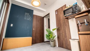 A compact kitchen with a microwave, a small refrigerator, and a potted plant. - Kujira 202 (Osaka)
