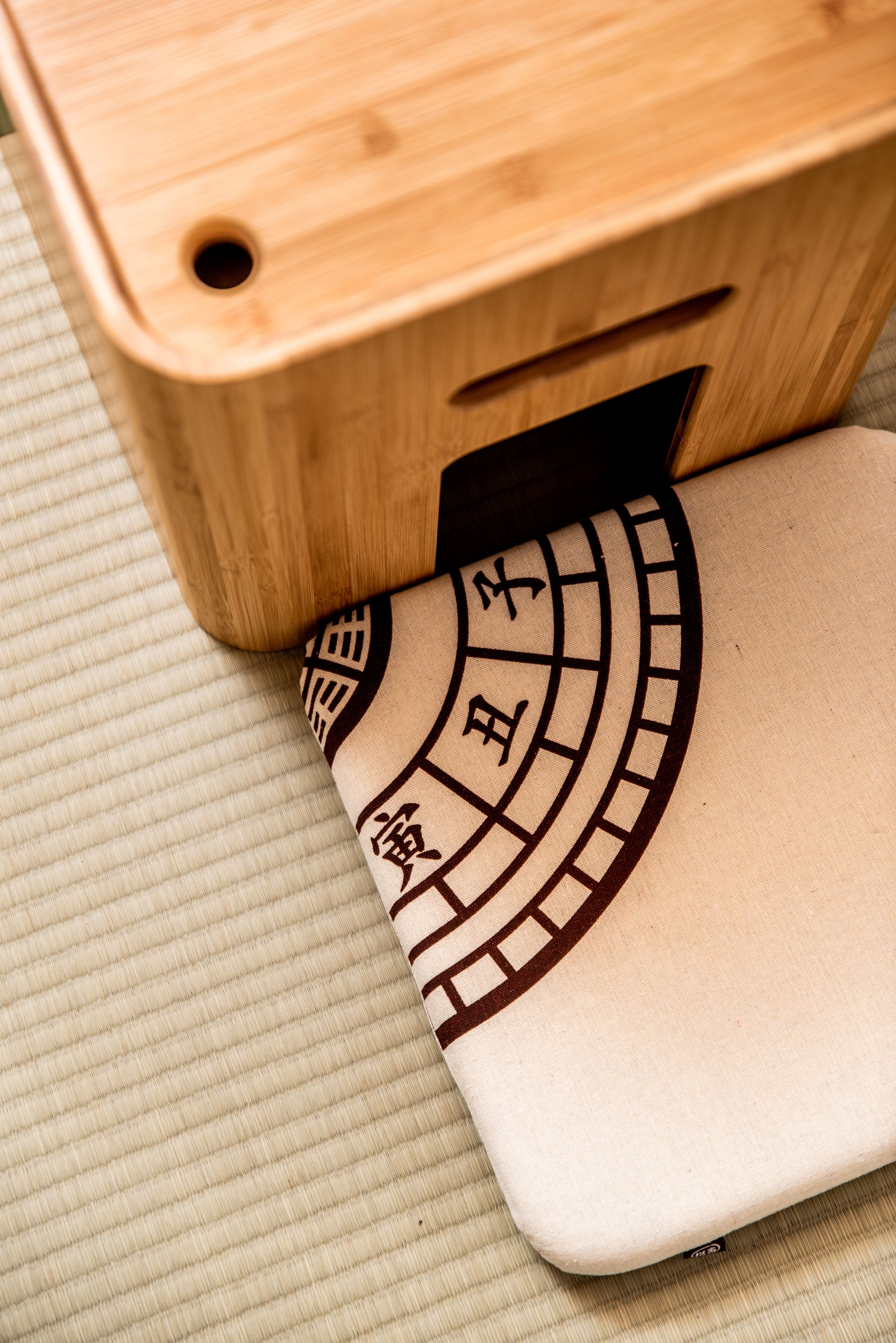 A wooden box with a circular design on its side, placed on a textured surface.